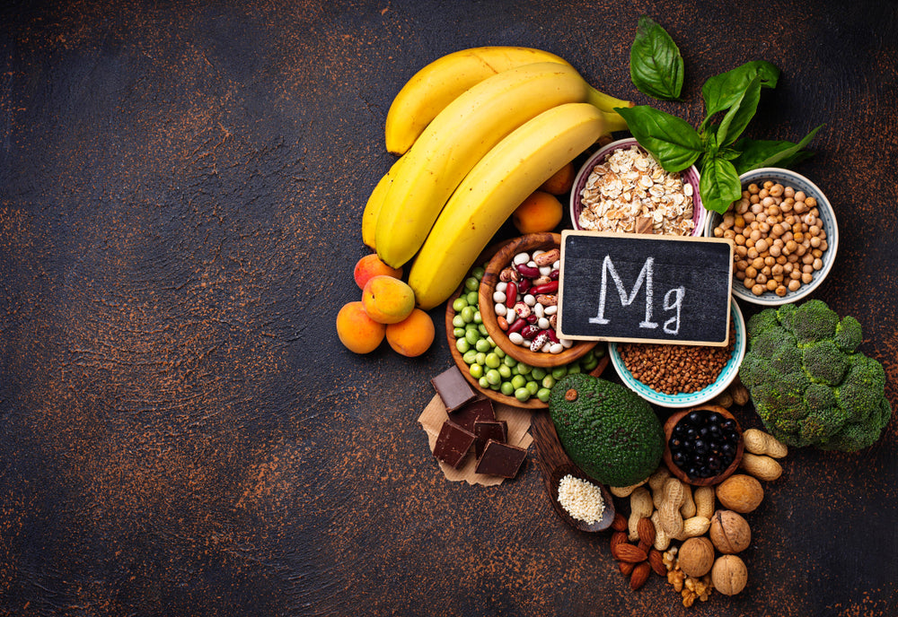 A group of magnesium rich foods under a chalk board sign showing "Mg" the scientific symbol for magnesium glycinate.